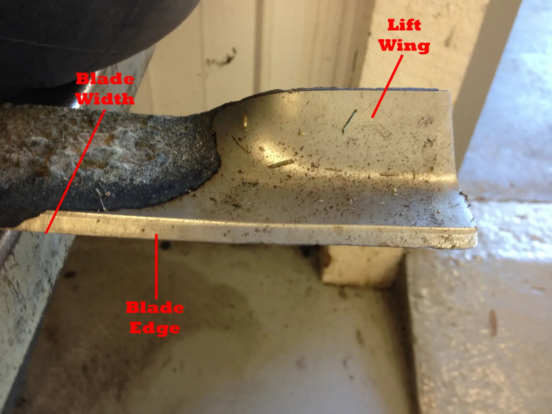 Close-up view of a lawnmower blade, highlighting blade width, edge, and lift wing.