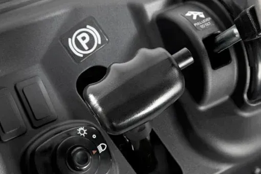 Dashboard controls: parking brake, headlights, and gear selector lever. Black with white symbols.