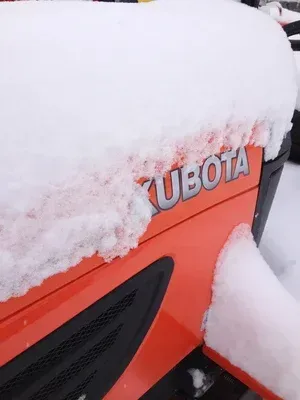 Orange Kubota tractor covered in snow.