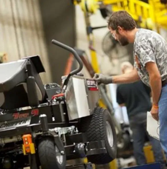 Man working on a lawnmower assembly line in a factory.
