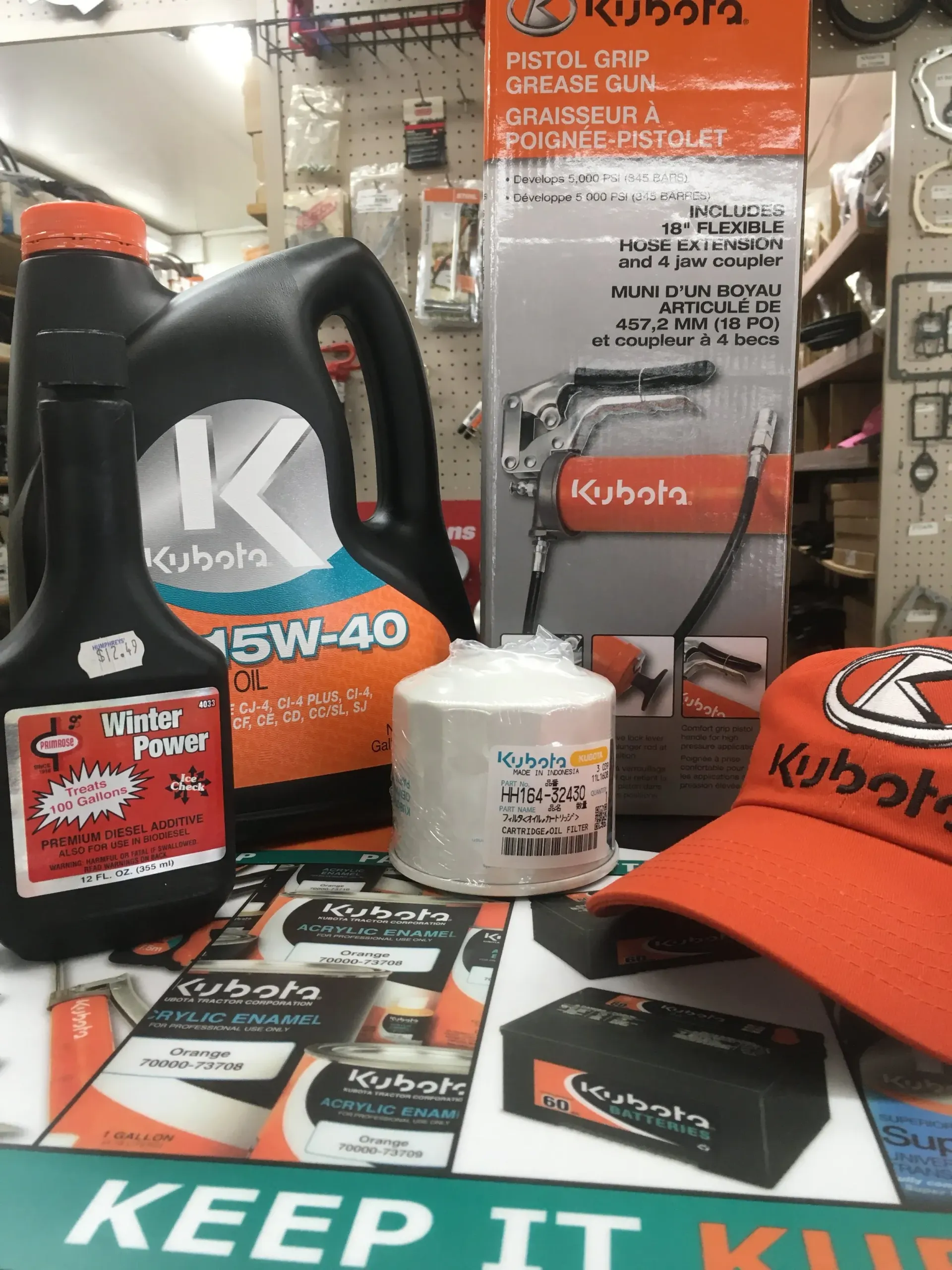 Kubota products, oil, filter, grease gun, cap, and marketing materials on a counter.
