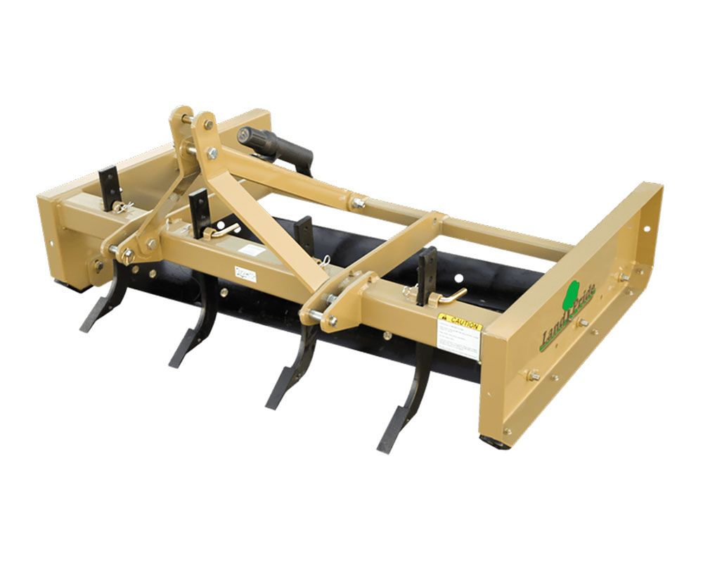 Tan box blade implement with ripper teeth, designed for use with a tractor.