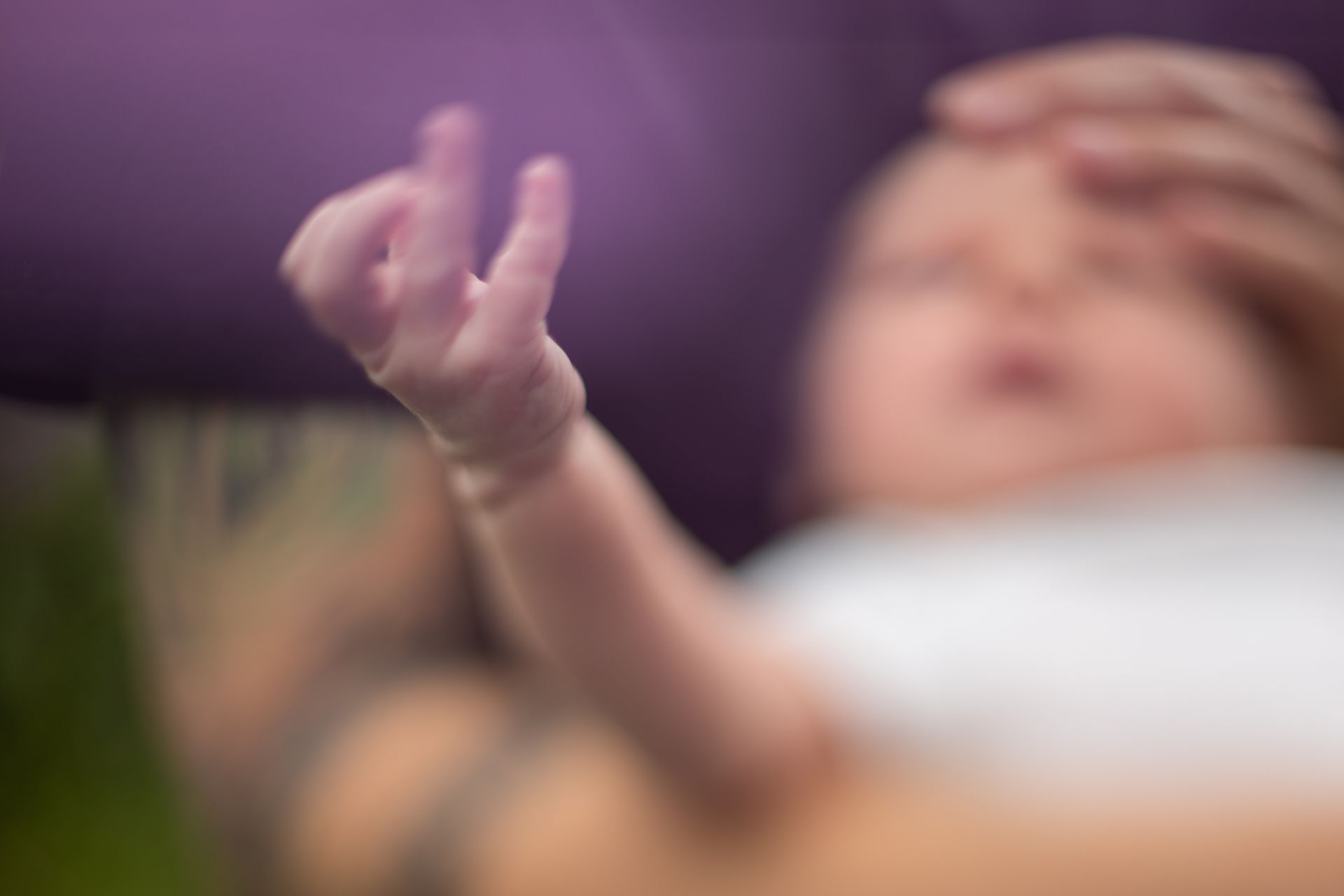 A blurry picture of a baby 's hand with a purple background.