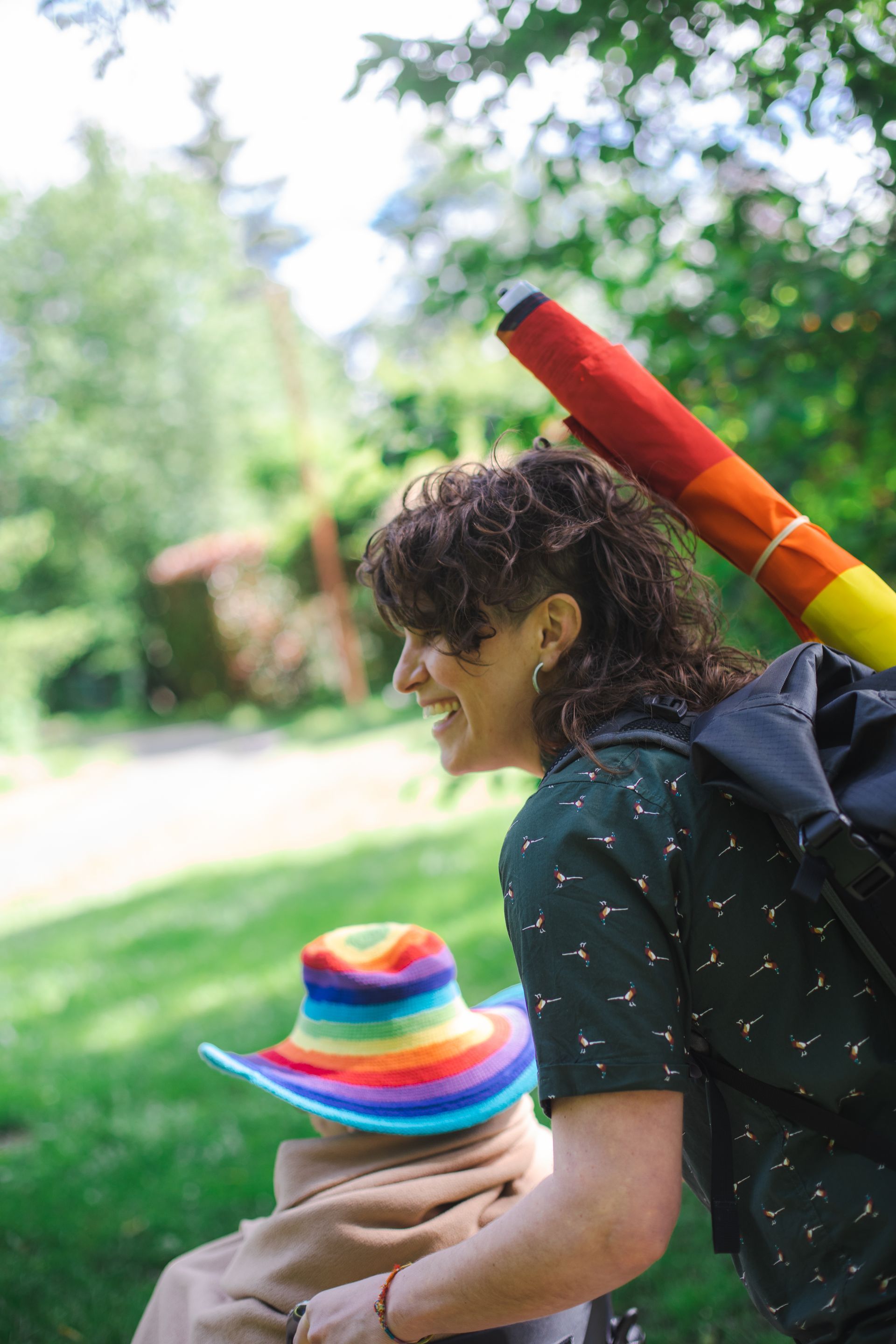A person with a backpack is with a person wearing a rainbow hat.
