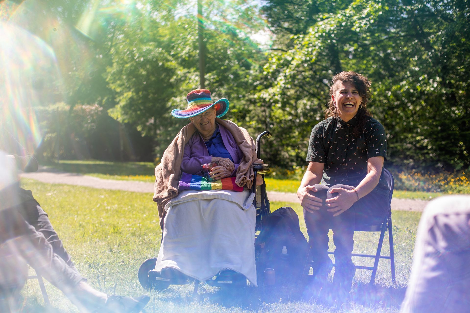 A person in a wheelchair is sitting in a circle with other people in a park.
