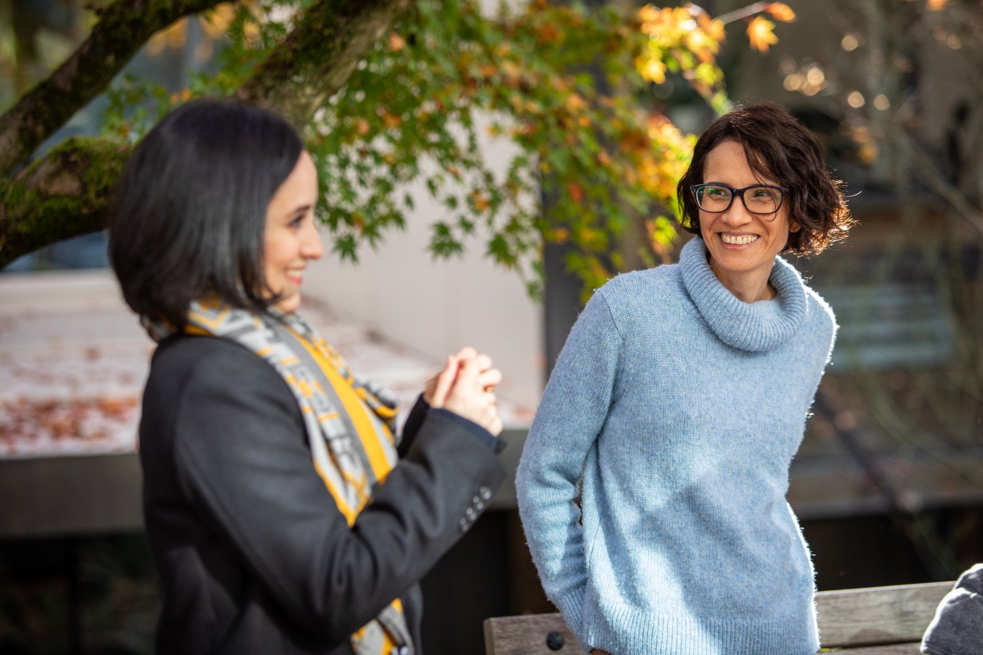 Two persons are standing next to each other on a bench.