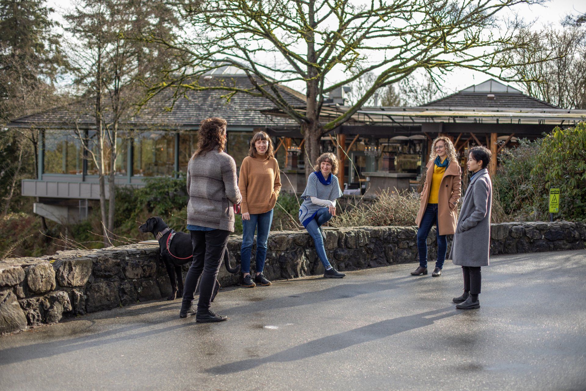 A group of people are sitting on a stone wall talking to each other.