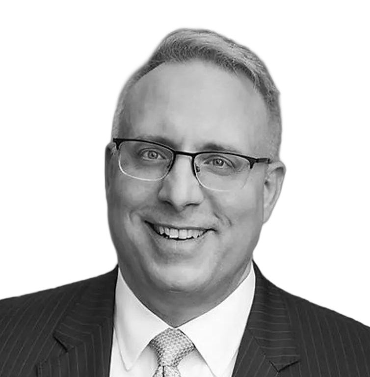 Man in suit and glasses looking to the side with a slight smirk.