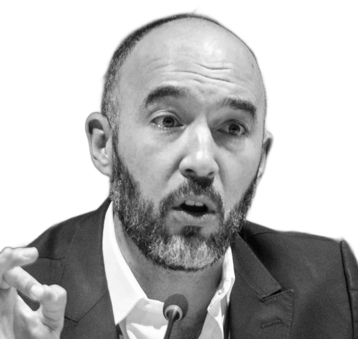 Man wearing glasses smiles, looking forward.