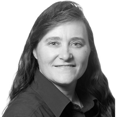 Woman with long hair, wearing a dark shirt, smiling, looking at the camera.