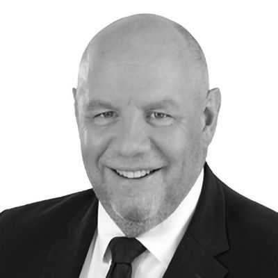 Smiling man in a suit, with a bald head and short beard, in a studio setting.
