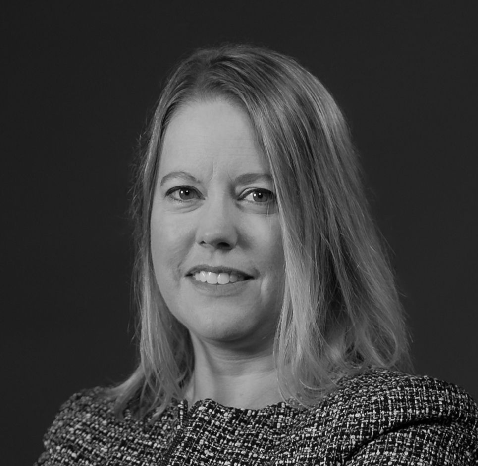 Man in a white button-down shirt smiles, looking at the camera against a white background.