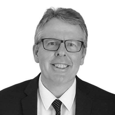 Man in glasses and suit, smiling at the camera.