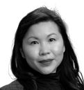 A portrait of a person with dark hair, wearing a dark turtleneck and a textured jacket, against a white background.