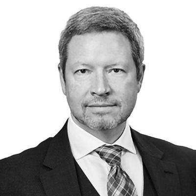 Man in a suit and tie, looking directly at the viewer with a neutral expression.