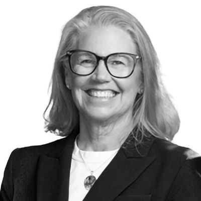 Woman wearing glasses, smiling, in a blazer.