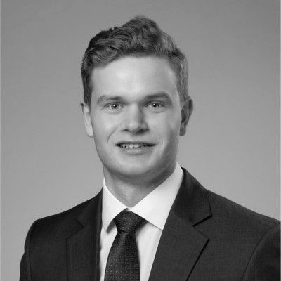 Man in suit and glasses looking to the side with a slight smirk.