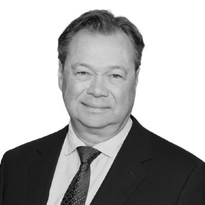 Man in a suit and tie, smiling at the camera. Black and white, formal portrait.