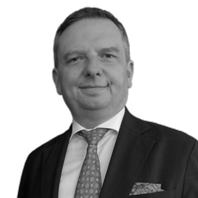 Smiling man in a suit, with a bald head and short beard, in a studio setting.