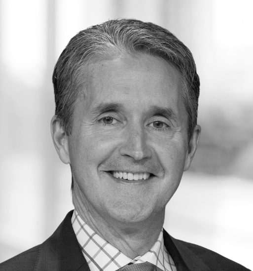 Man in suit and glasses looking to the side with a slight smirk.