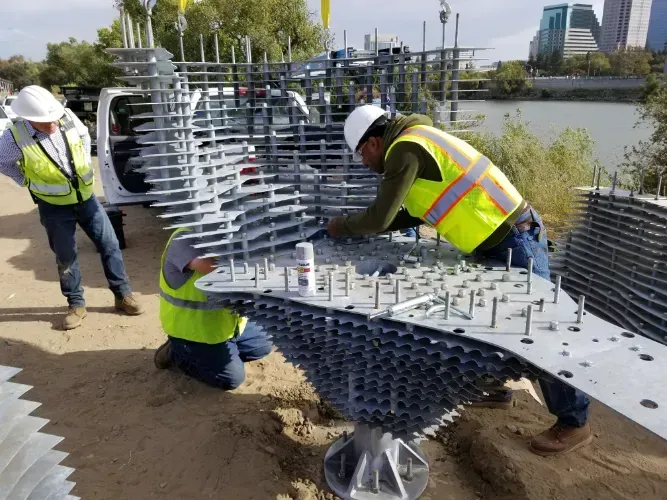 A group of construction workers are working on a large metal structure.
