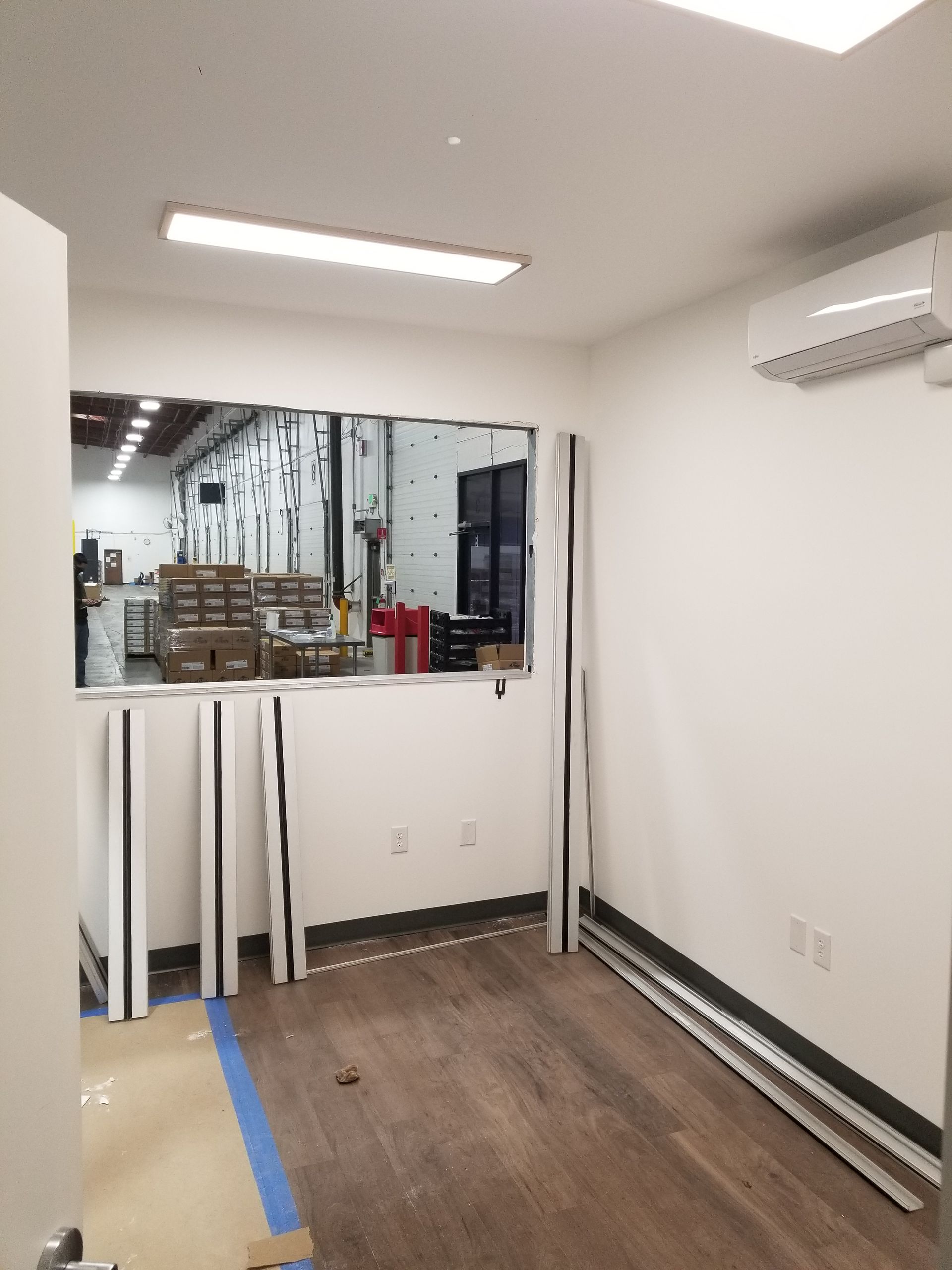 A room with a window that looks out to a warehouse.