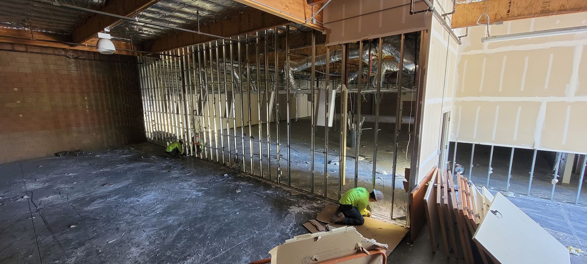 A man in a green shirt is standing in a room with a lot of concrete.