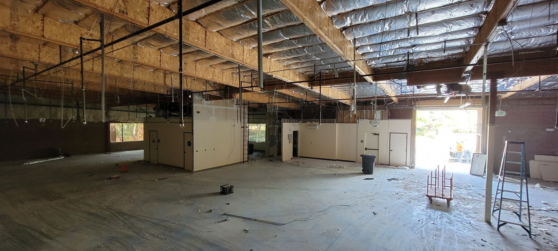 A large empty room with a lot of pipes hanging from the ceiling.