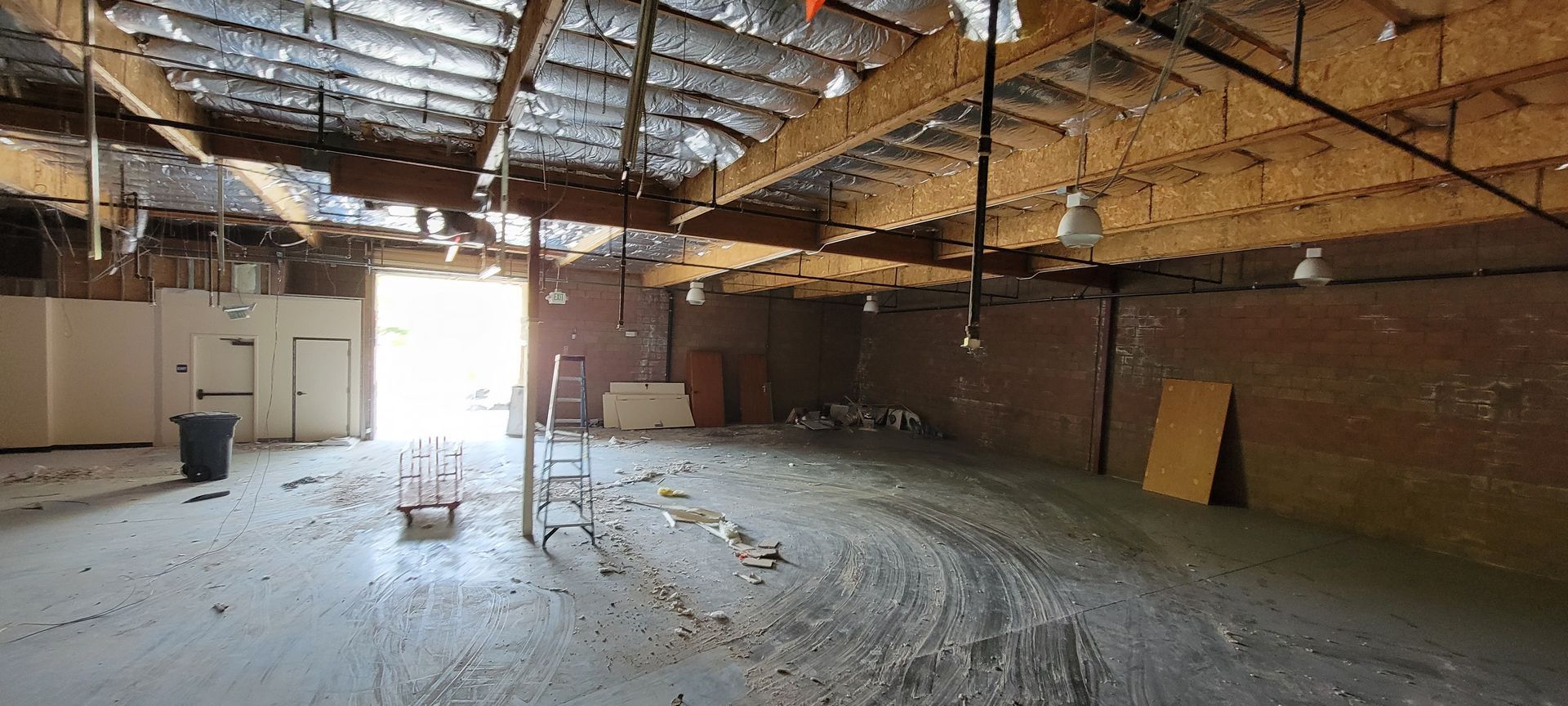 A large empty room with a wooden ceiling and a brick wall.