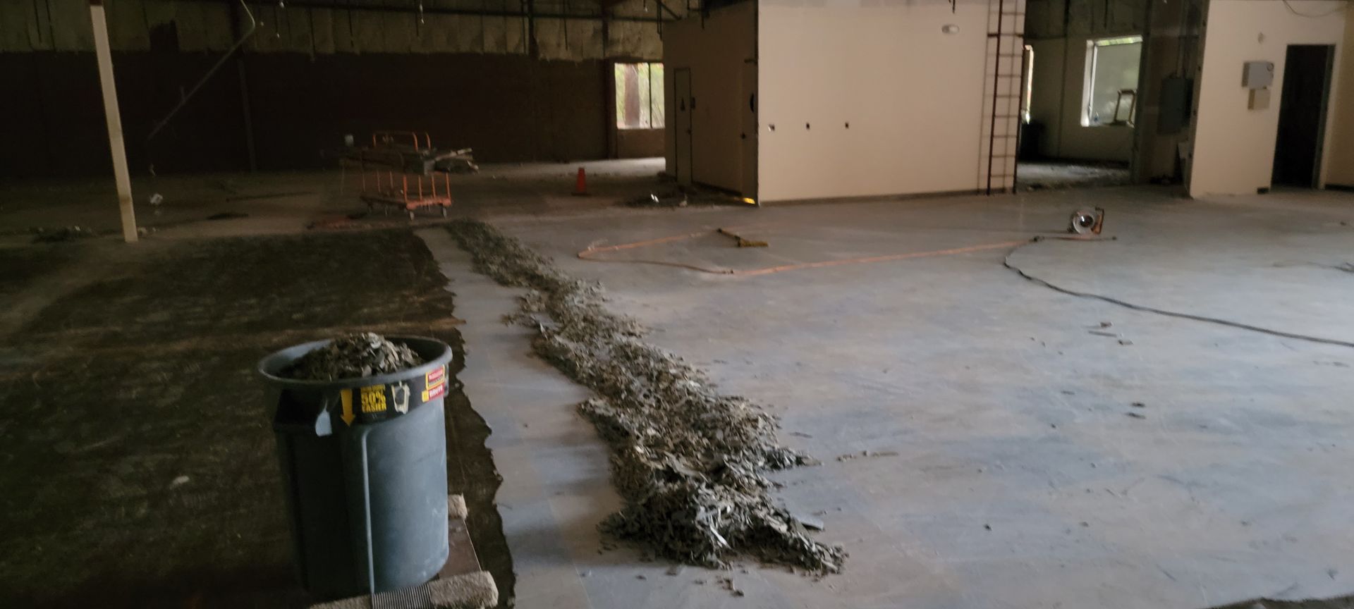 A large empty room with a trash can in the middle of it.