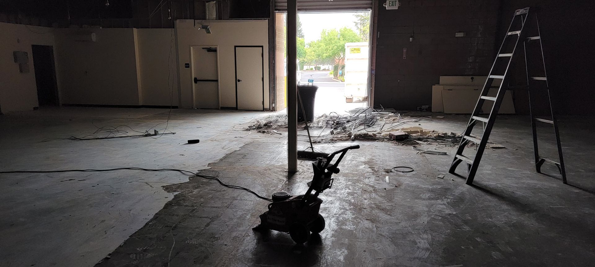 An empty warehouse with a ladder and a scooter on the floor