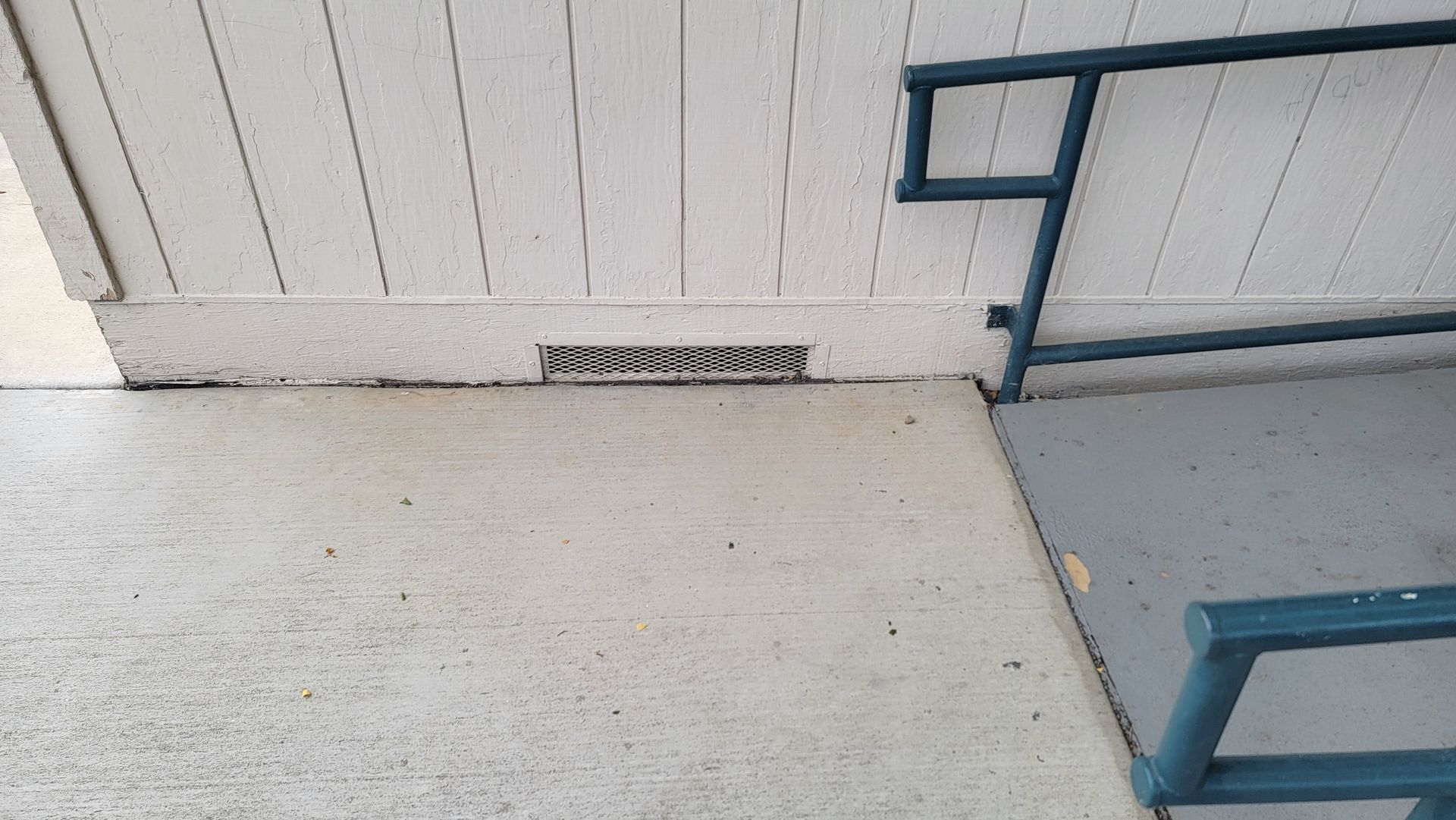 A drain on the side of a building next to a staircase.