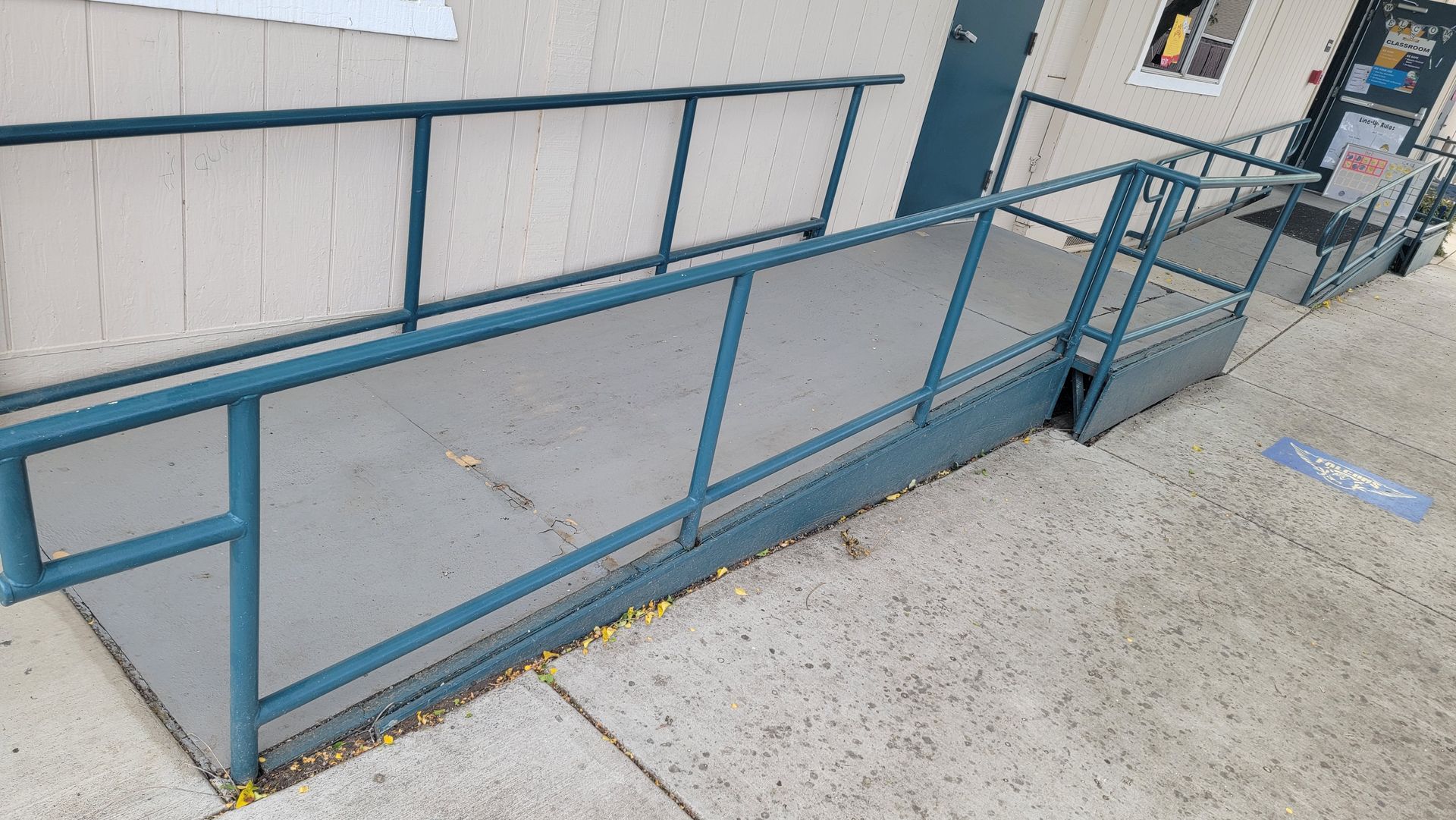 A ramp with a blue railing is leading to a building.