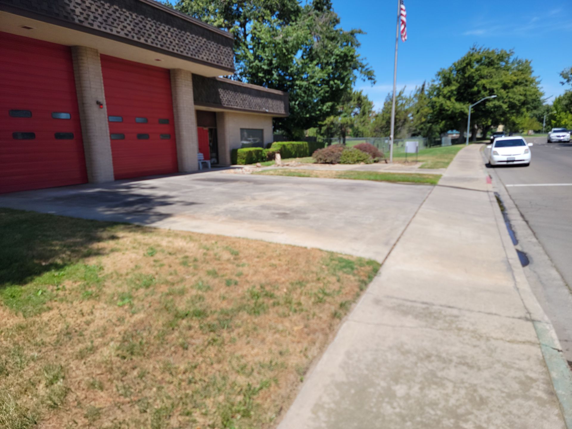 A white car is parked in front of a red garage door.