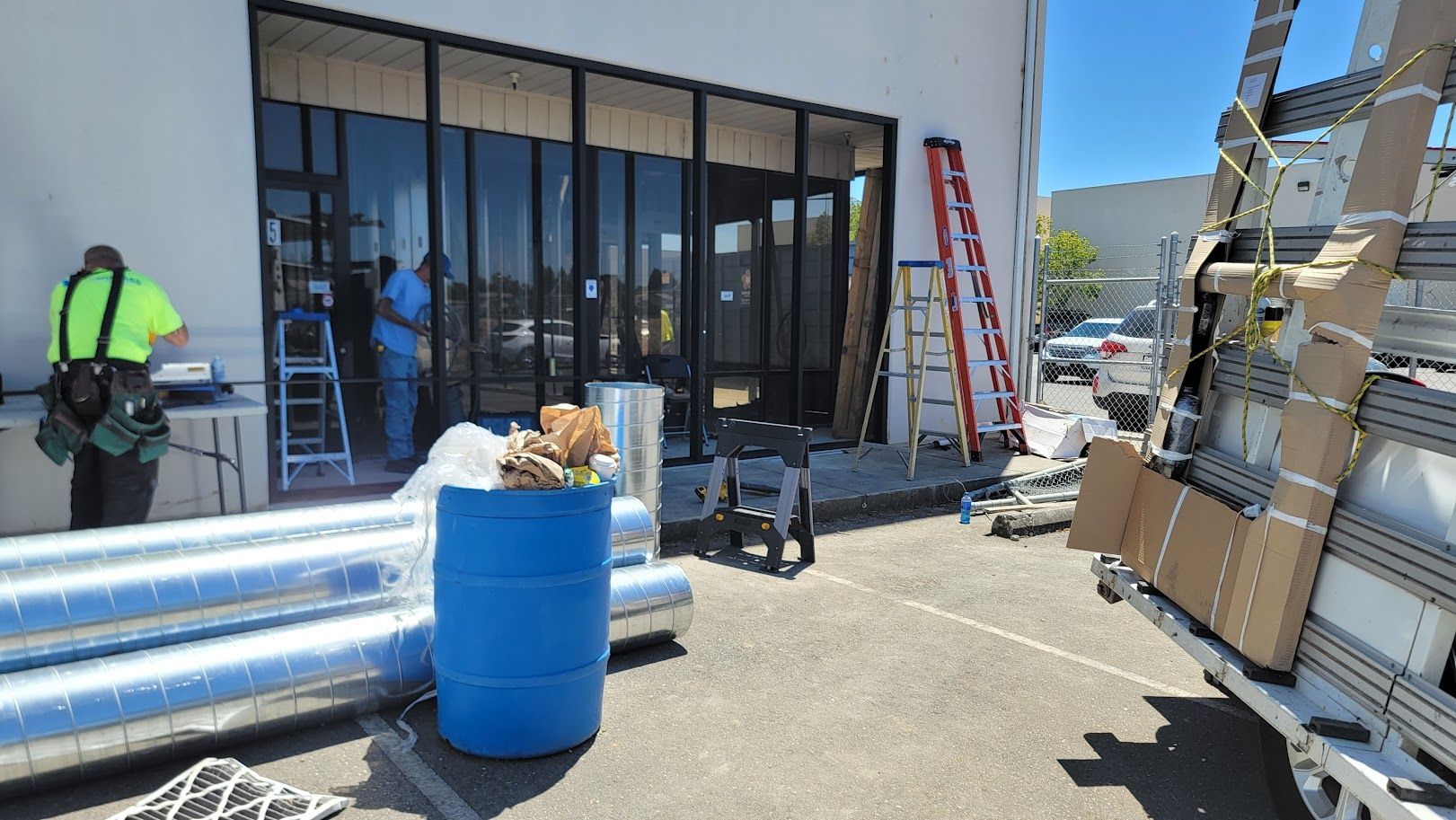 A blue barrel is sitting in front of a building under construction.