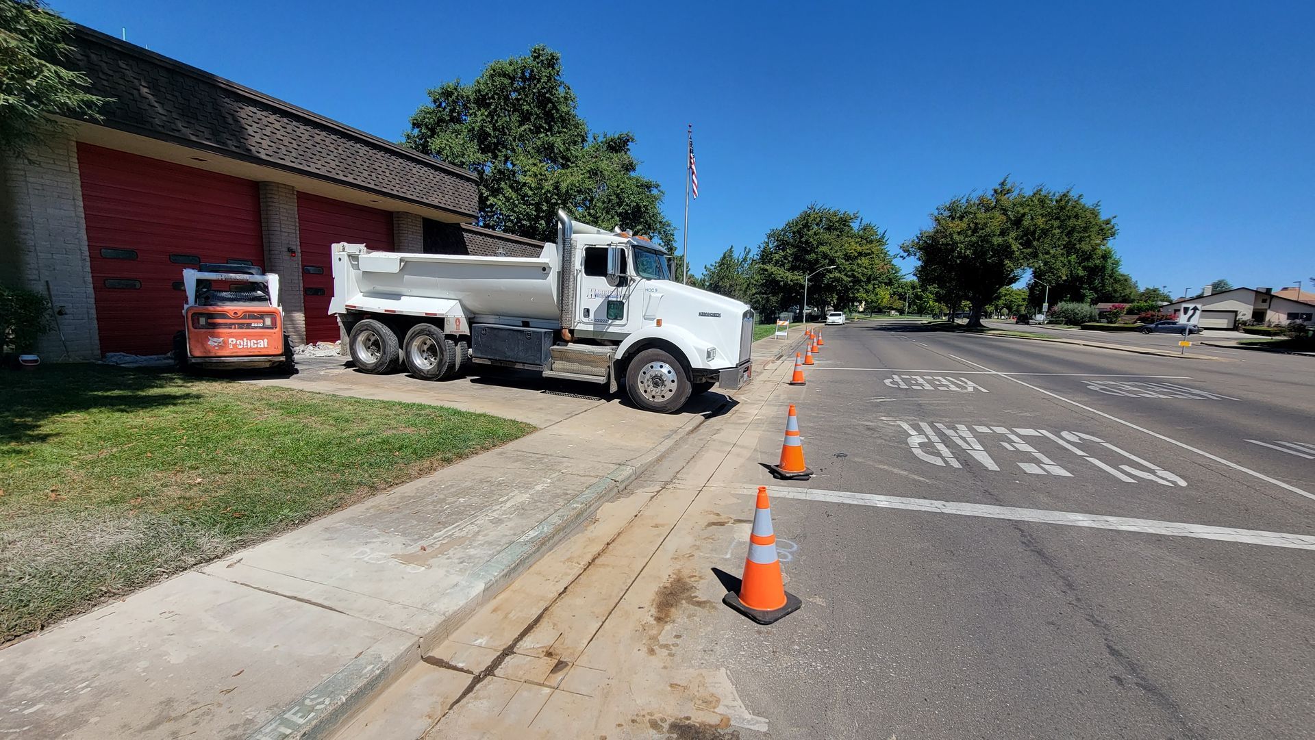A white dump truck is parked on the side of the road.