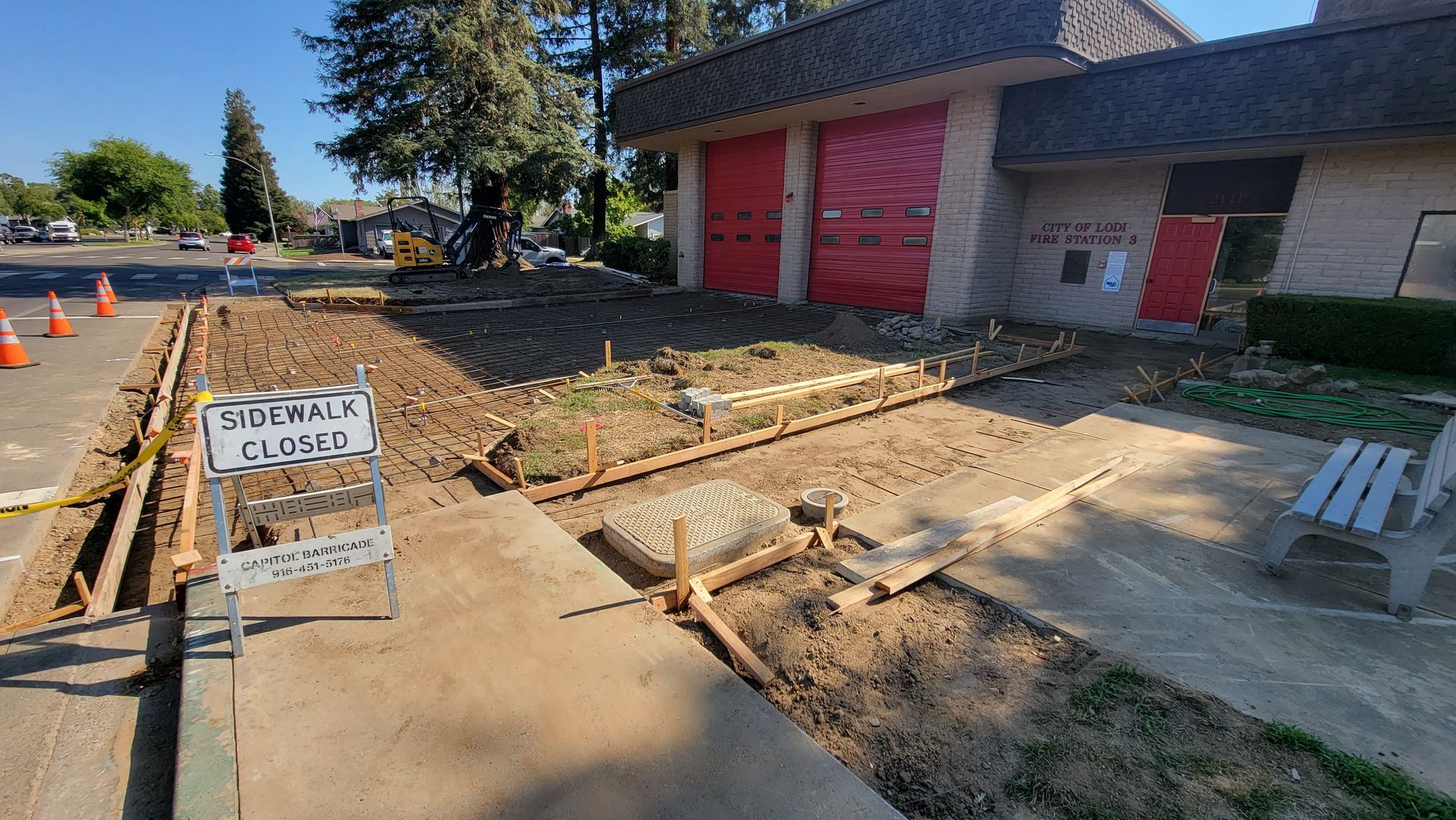 A concrete walkway is being built in front of a fire station.