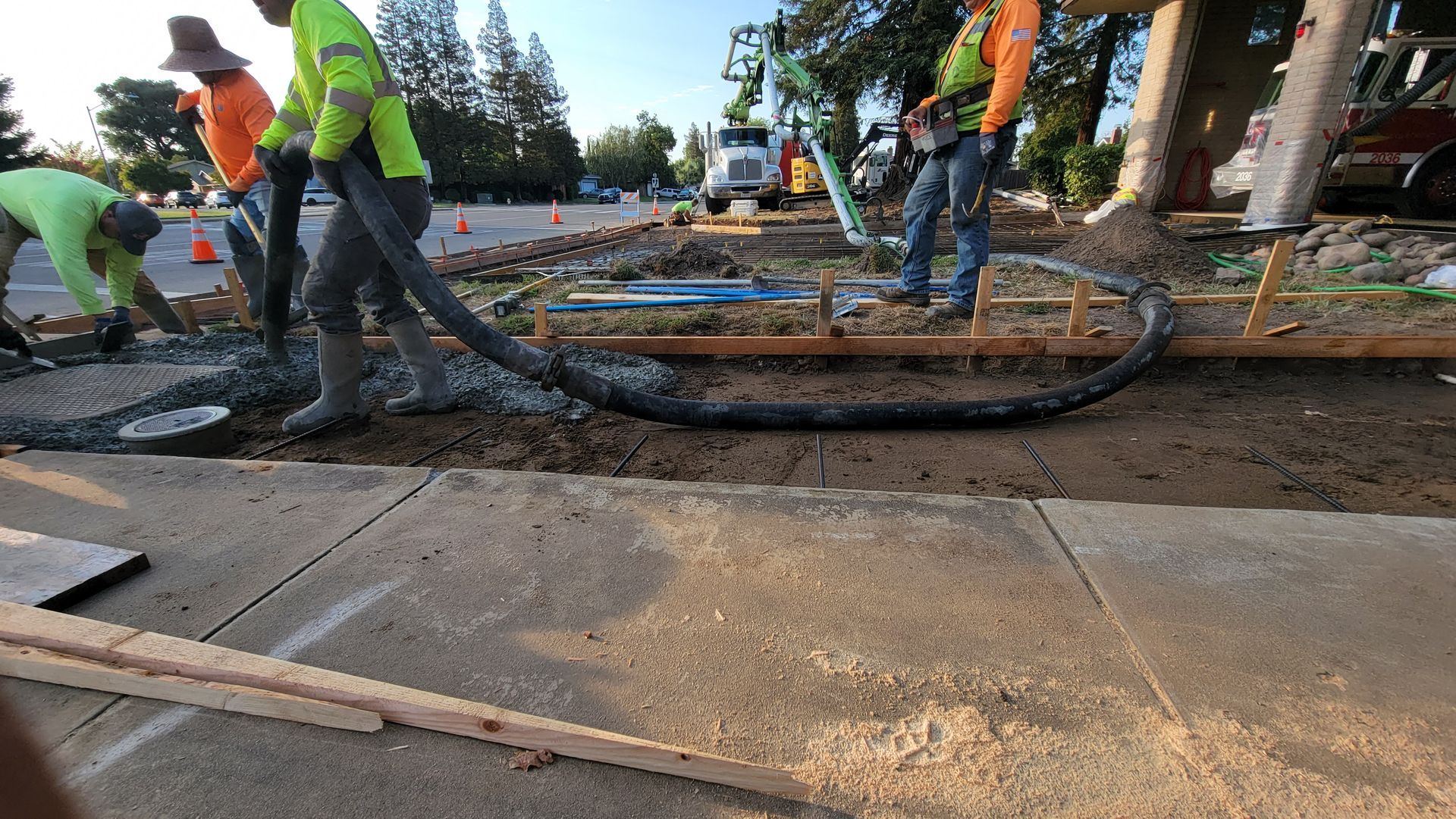A group of construction workers are working on a sidewalk.