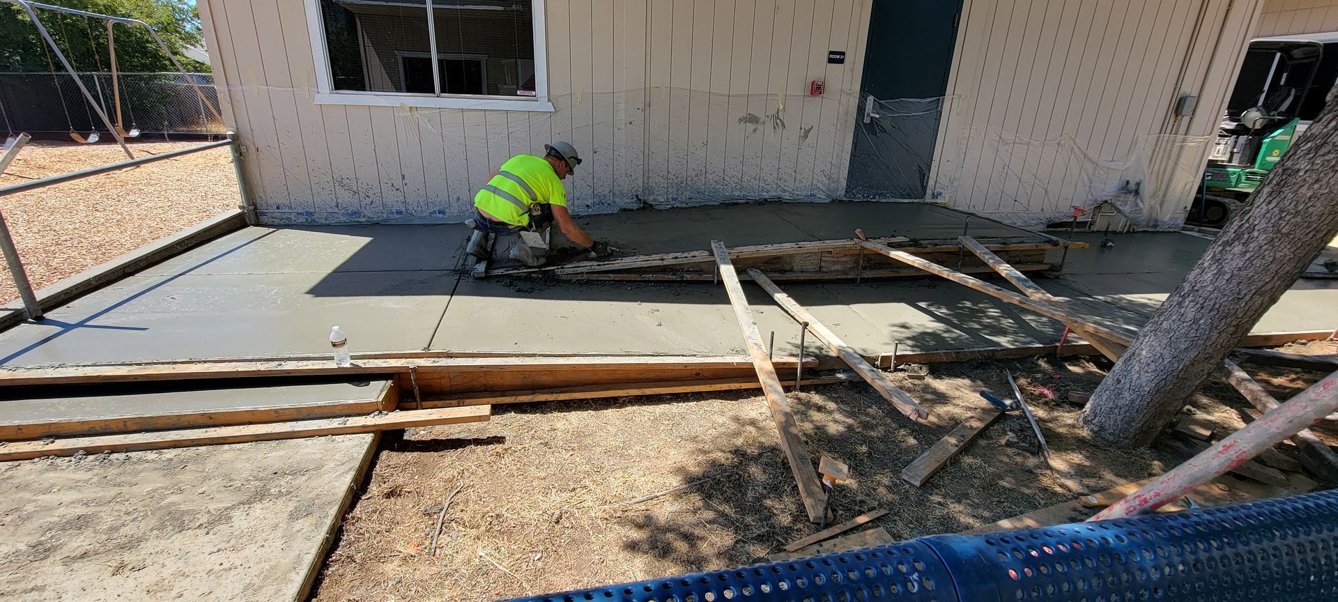 A man is laying concrete in front of a house.
