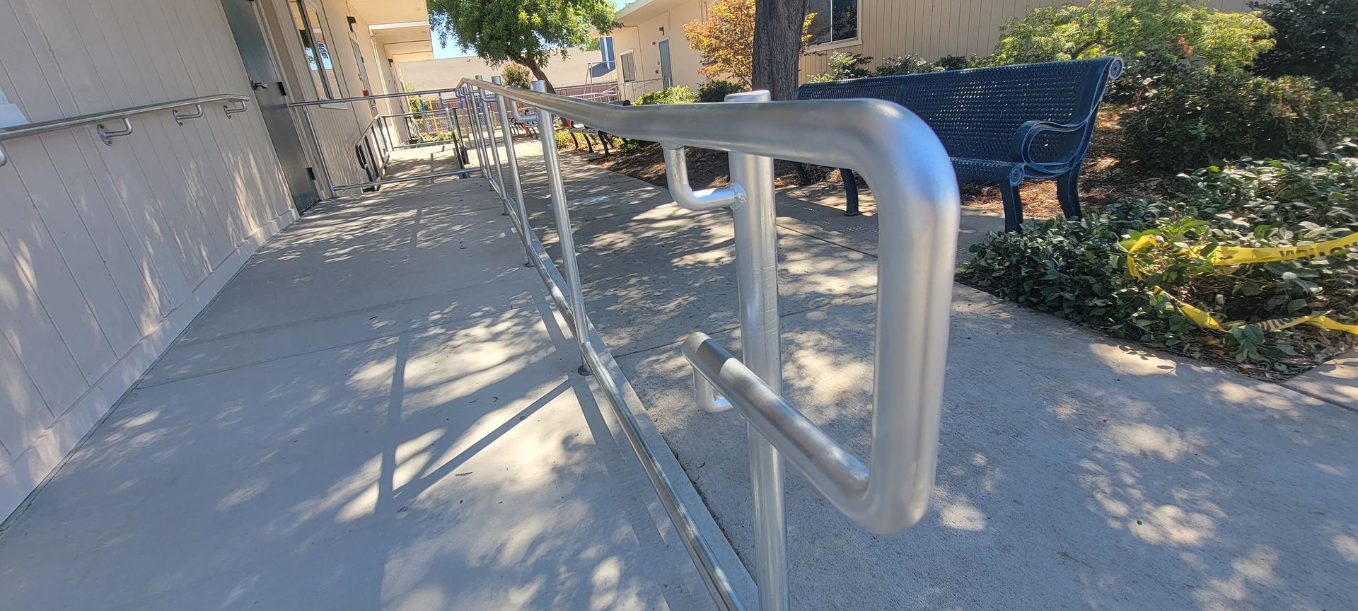 A metal railing on a sidewalk next to a building.