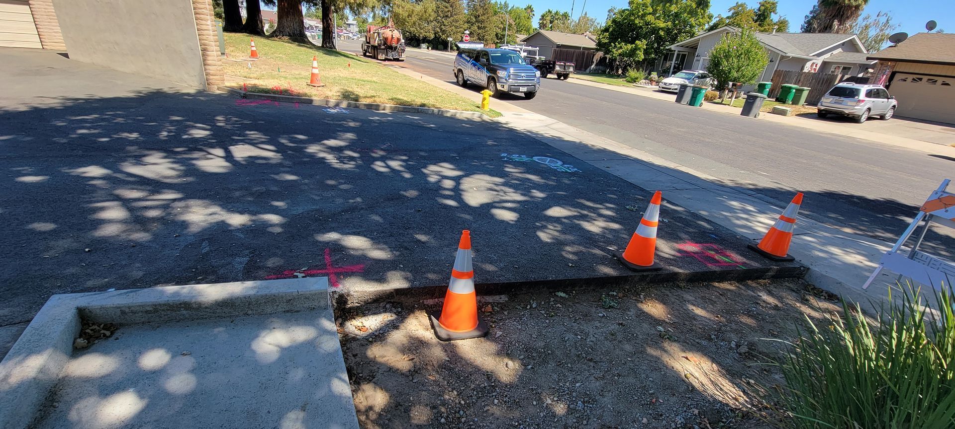 A group of orange and white traffic cones are sitting on the side of a road.