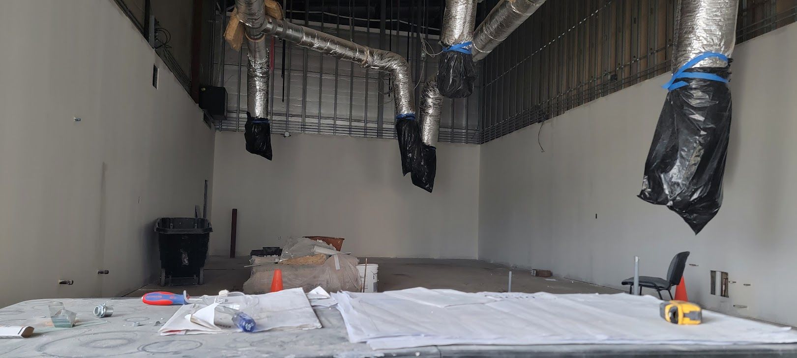 A large empty room with a lot of pipes hanging from the ceiling.