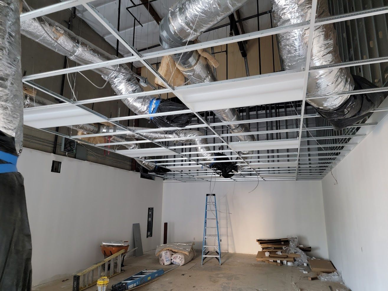 A room with a ceiling that is being built and a ladder.