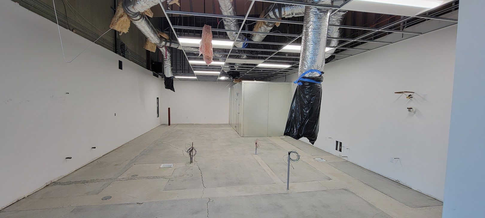 A large empty room with white walls and a ceiling that is being remodeled.