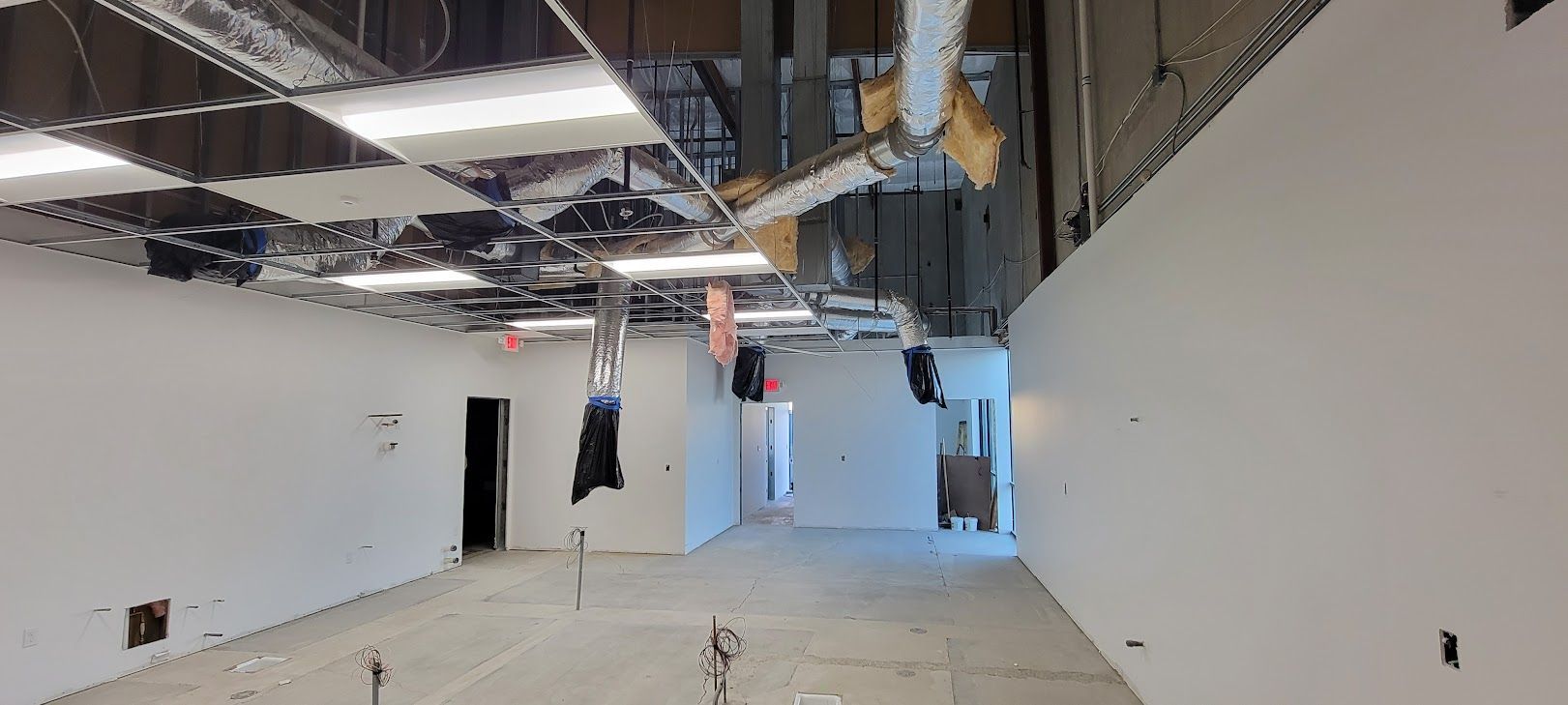 A large empty room with white walls and a ceiling that is being remodeled.