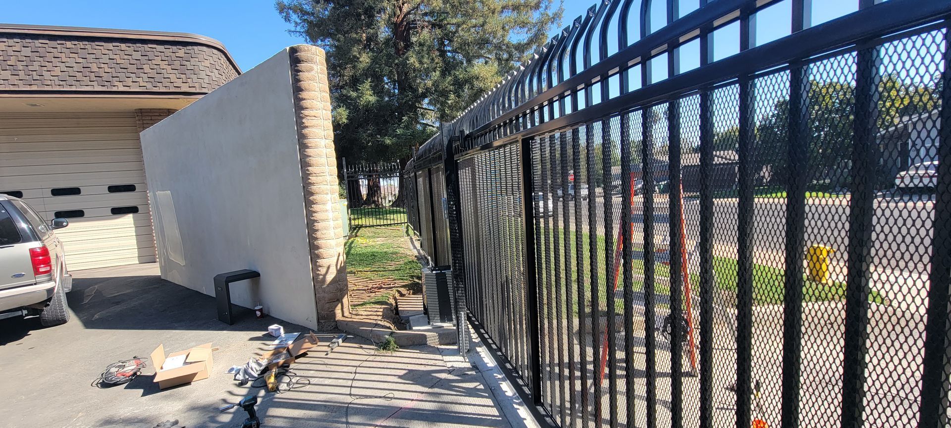 A black metal fence is being installed in front of a house.