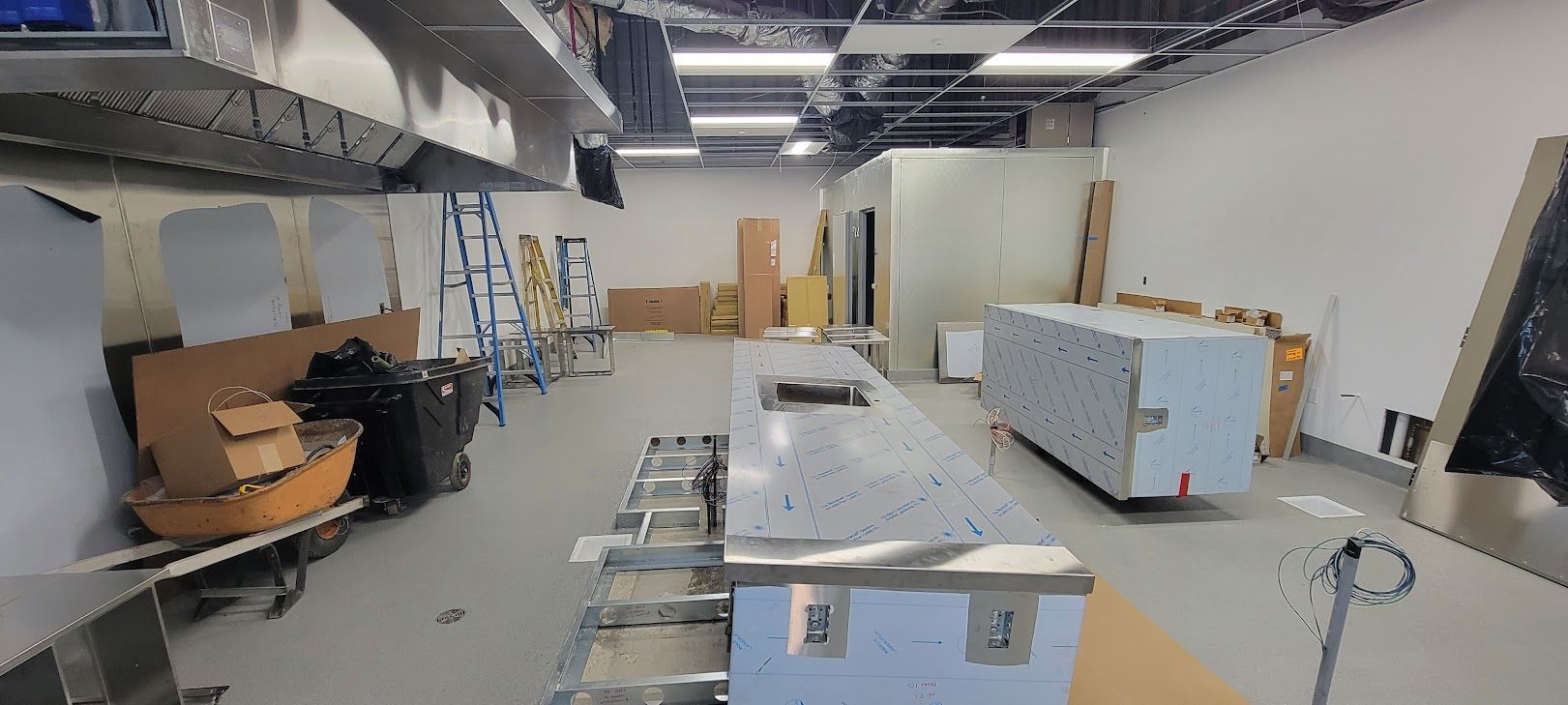 A kitchen is being built in a building with stainless steel appliances.