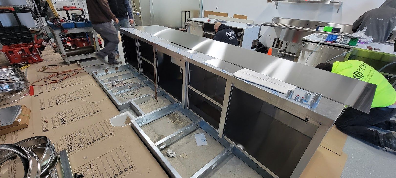 A man is working on a stainless steel counter in a kitchen.