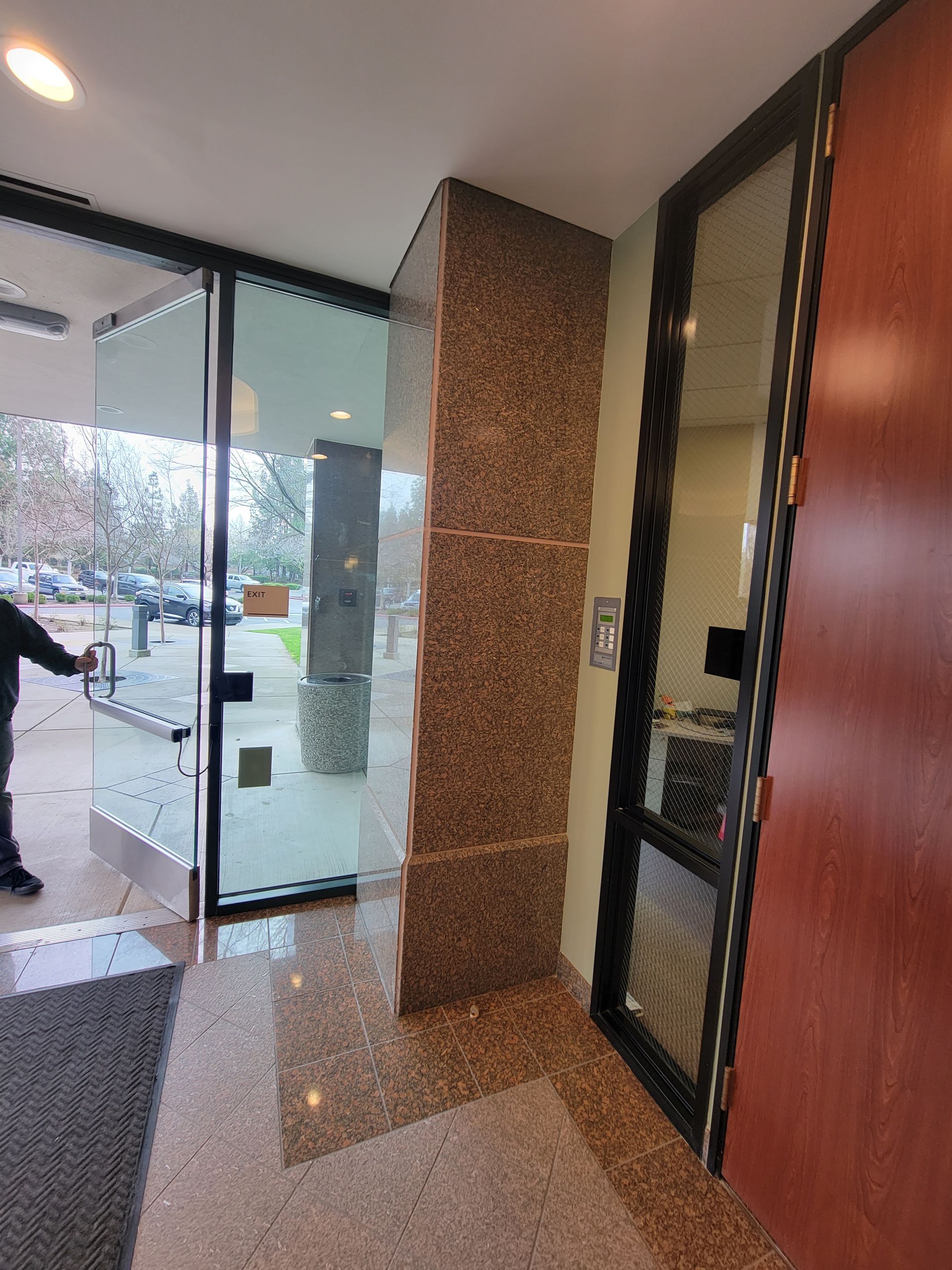 A man is standing in a hallway with a glass door.