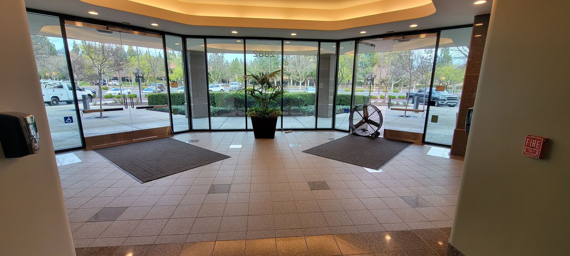 A large lobby with a lot of windows and a plant in the middle.